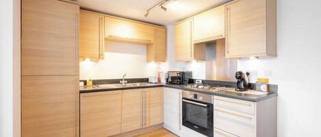 A modern kitchen with wooden cabinets, a built-in oven, and a countertop with various appliances.