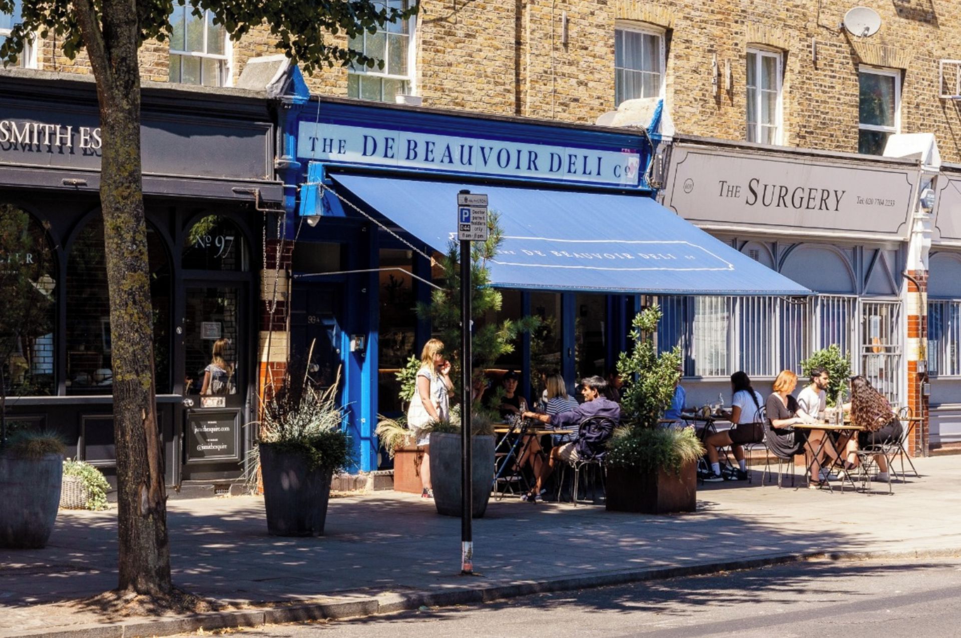 An outdoor café with tables and chairs, surrounded by buildings with visible signage.