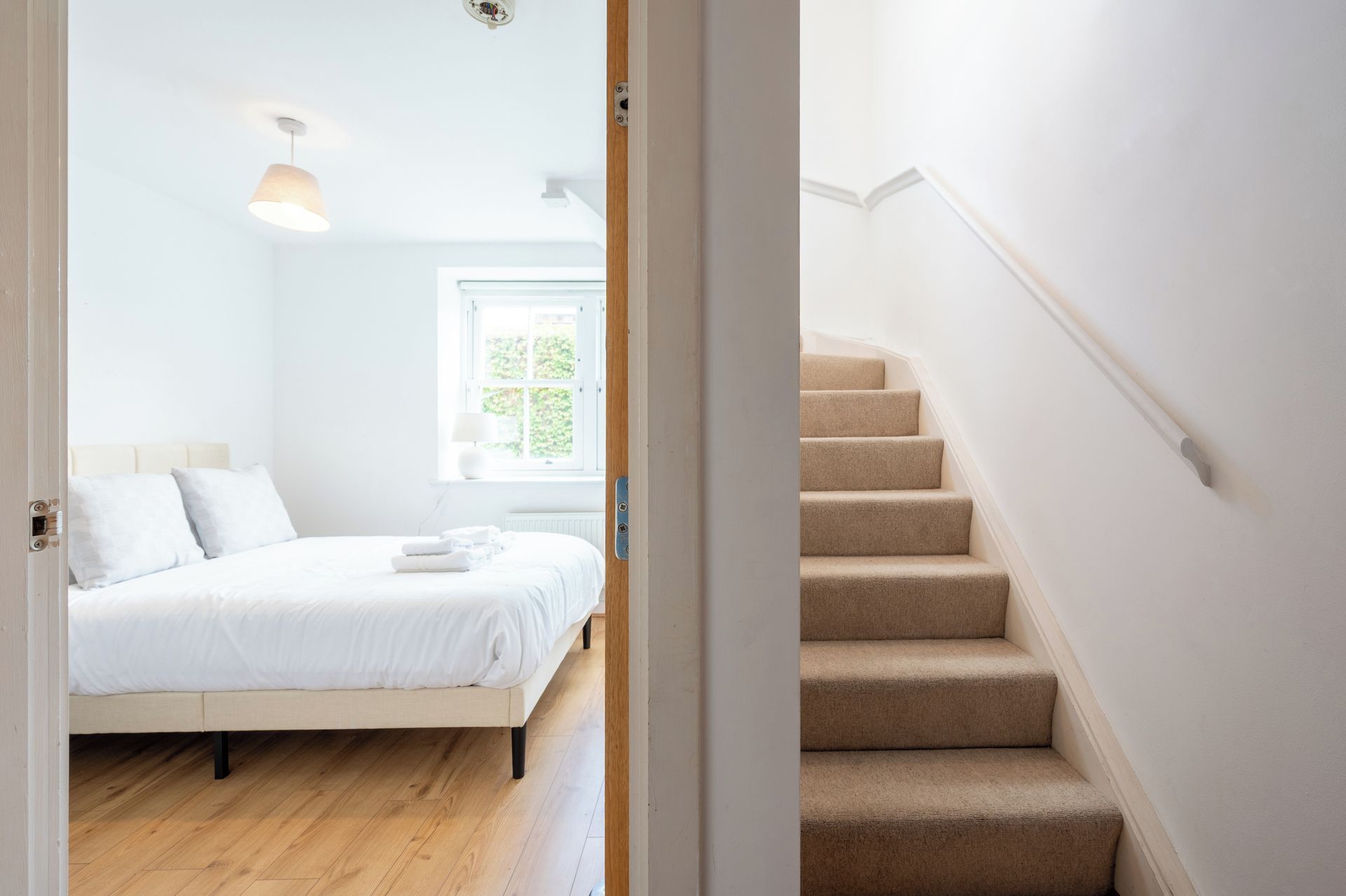 Een slaapkamer met een bed, een raam en een trap.