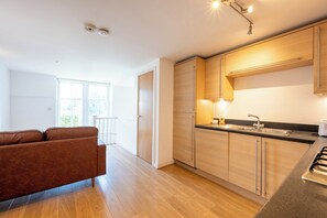 A modern kitchen with wooden cabinets, a black countertop, and stainless steel appliances. - Chic 1BDR Flat in De Beauvoir Town (London)