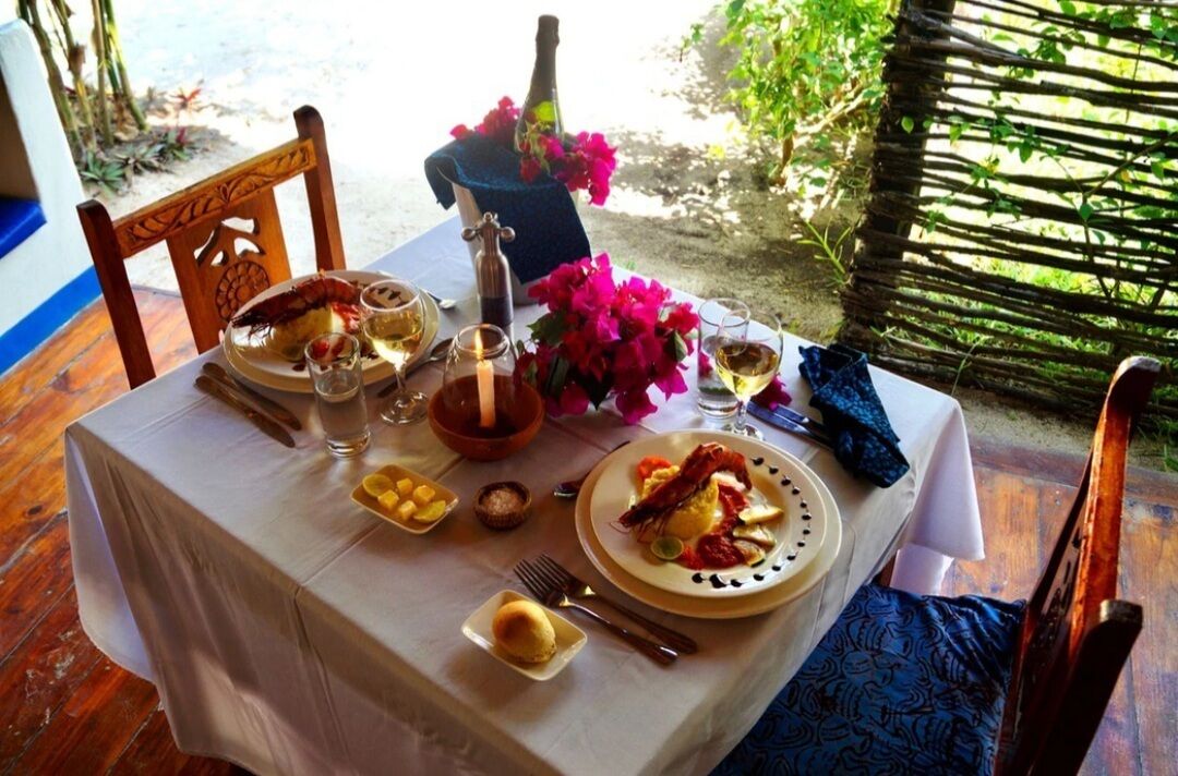 Una mesa dispuesta para una comida, con platos, vasos y una botella.