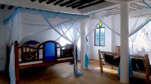 Una habitación con cama, una hamaca y un ventanal con diseño de vitral.