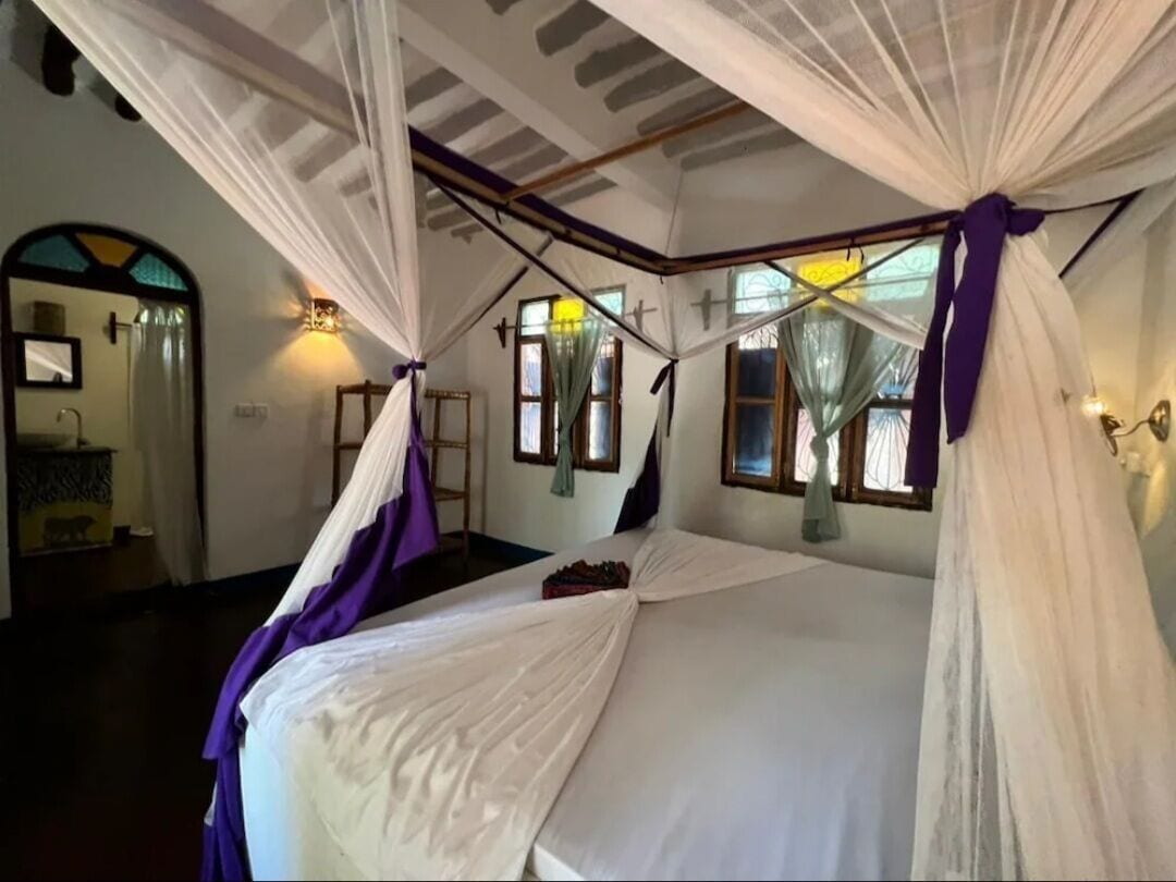Una habitación con una cama, un espejo y una ventana.