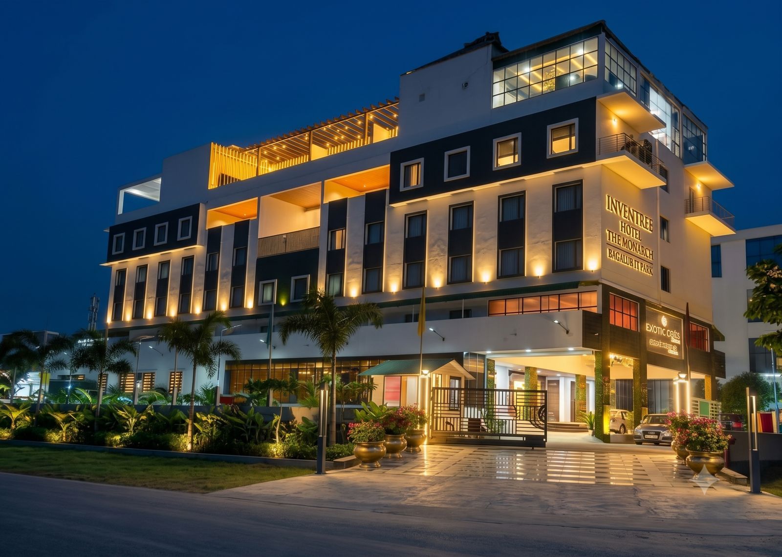 Een meerlaags hotel met een modern design, met balkons en een goed verlichte entree.