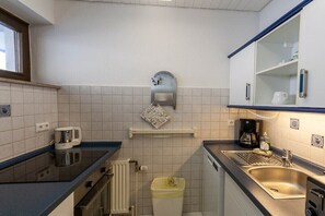 Eine kleine Küche mit Kaffeemaschine, Spüle und Mülleimer.
