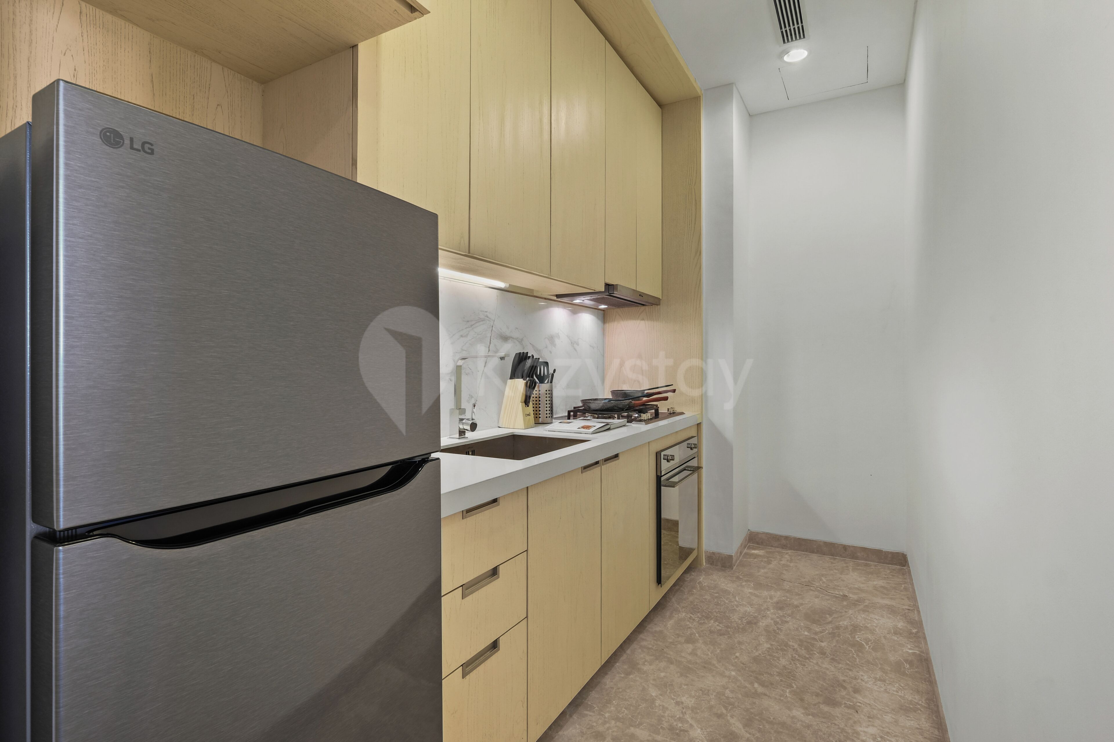 A modern kitchen with a stainless steel LG refrigerator, wooden cabinets, and a white countertop.