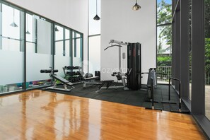 A gym with exercise equipment, large windows, and a wooden floor. - Karven by Kozystay - Cilandak (South Jakarta)