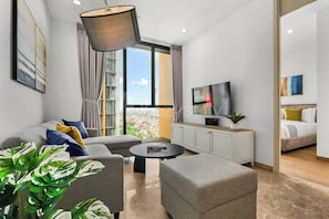 Een moderne woonkamer met een bank, fauteuils, een salontafel, een televisie en een boekenkast.