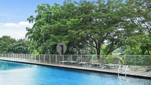 A swimming pool with lounge chairs and a deck. - Karven by Kozystay - Cilandak (South Jakarta)