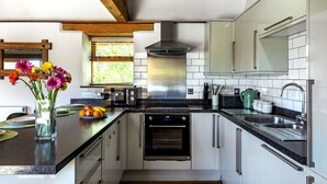 A modern kitchen with white cabinets, stainless steel appliances, and a wooden ceiling. - The Old Piggery at Rusty Lane Farm (Seend)