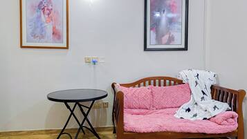 Et værelse med en træsofa, et lille rundt bord og to billeder i rammer på væggen.