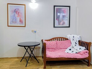 A room with a wooden sofa, a small round table, and two framed artworks on the wall. - Malachite Birdsong Retreat Apt 8 (Kampala)