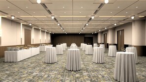 A conference room with round tables, a buffet table, and a stage.