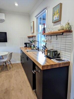 A modern kitchen with a wooden countertop, a built-in oven, and a window above the sink.