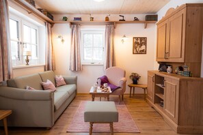 A cozy living room with a sofa, armchair, coffee table, and wooden cabinet. - Chalet at the Zlaim lift with sauna (Grundlsee)