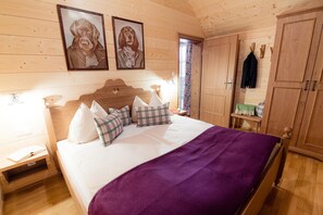 Ein Schlafzimmer mit Holzwänden, einem Bett, zwei gerahmten Bildern an der Wand und einem Holzschrank.