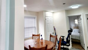 A dining area with a wooden table, chairs, a vase, and a bottle of dish soap.