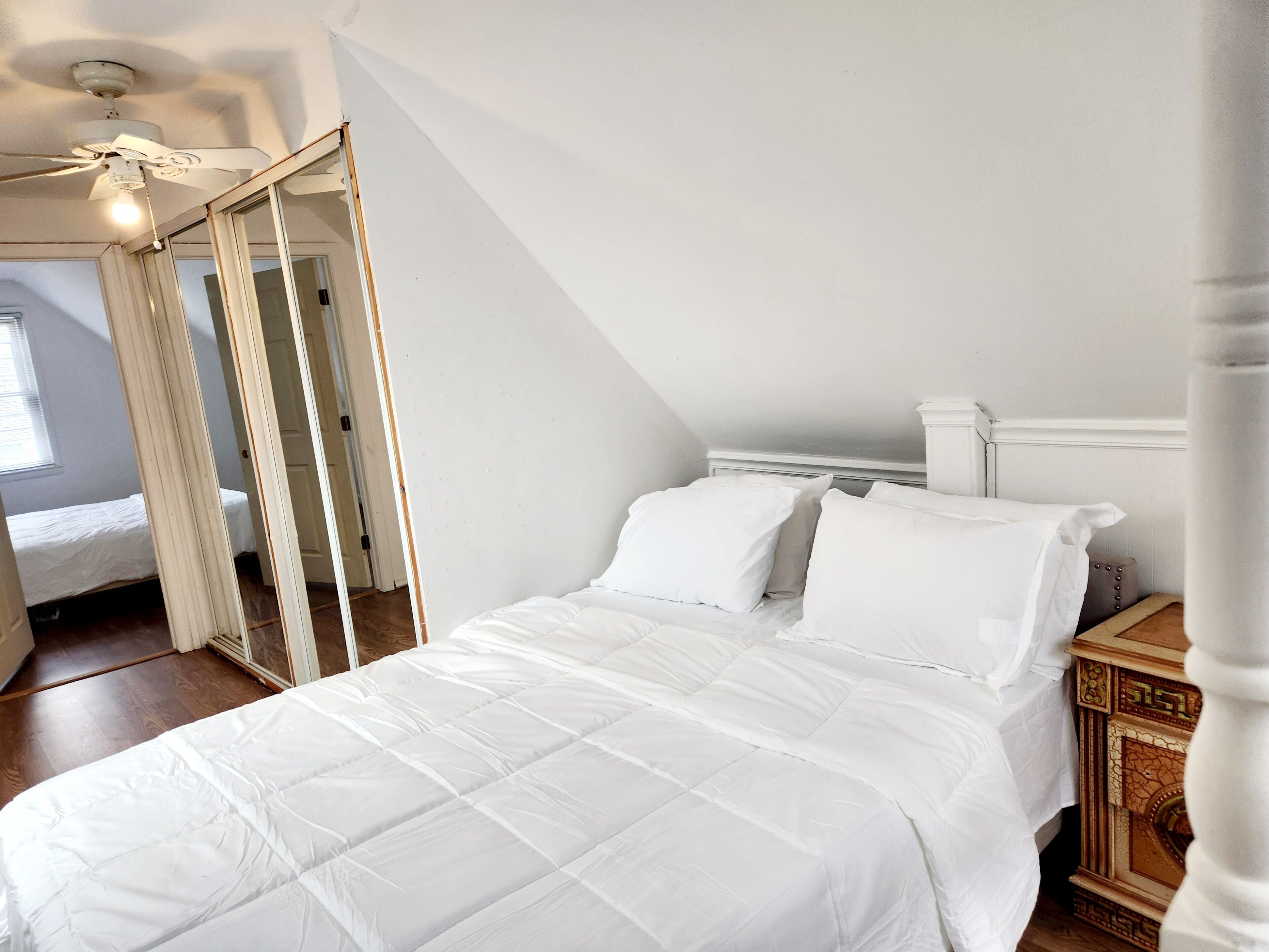 Een slaapkamer met een groot bed, een houten nachtkastje en een klassieke open haard.