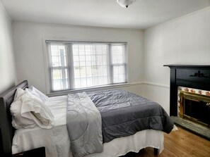 Un dormitorio con cama, ventana con persianas y chimenea.