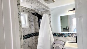 A bathroom with a shower, a sink, a mirror, and a towel rack.
