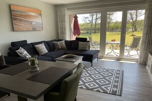 Una sala de estar moderna con un sofá seccional, una mesa de comedor y vistas al exterior.