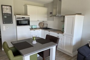 Eine kleine Küche mit weißen Schränken, einem Einbauofen, einem Toaster und einem Spülbecken.