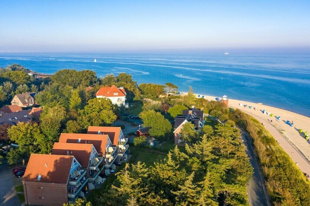 A coastal residential area with houses, a beach, and a lighthouse in the distance.