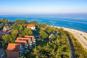 Zona residencial costera con casas, una playa y un faro a lo lejos.
