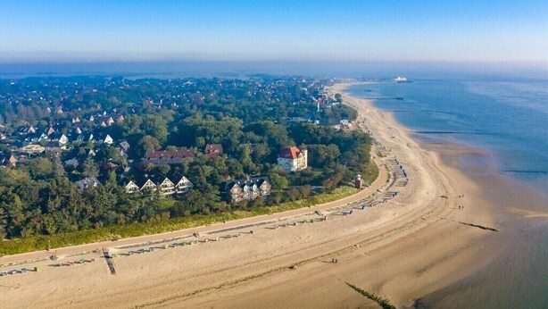 Eine Küstenstadt mit Strand, Häusern und einem Leuchtturm.