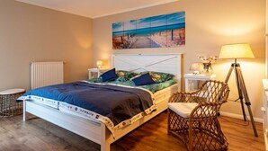 A bedroom with a bed, a chair, a lamp, and a painting on the wall. - Bel blue, Residence Bel Vital (Binz)