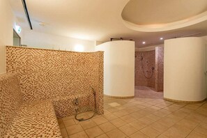A spa room with a patterned wall, a massage table, and a shower area. - Bel blue, Residence Bel Vital (Binz)