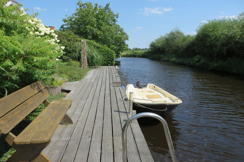 A wooden dock with a bench and a small boat moored at the end.