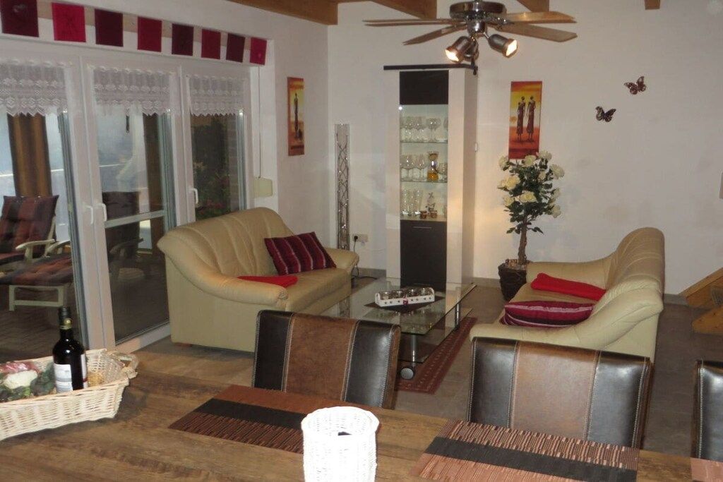 A living room with a sofa, chairs, a glass coffee table, and a dining table with chairs.