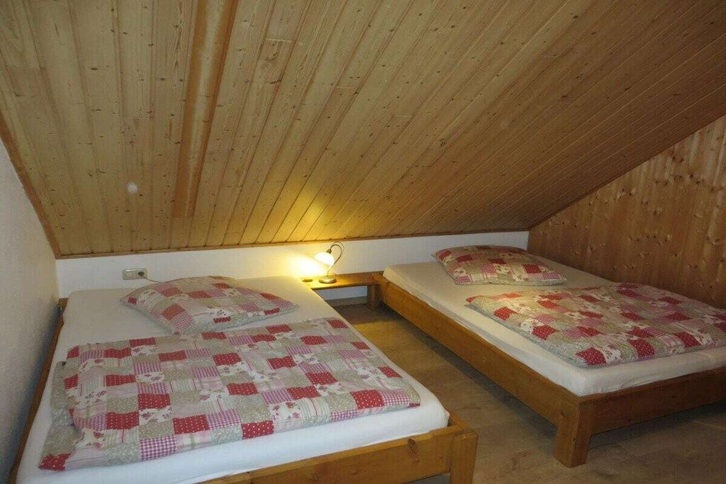 Ein kleiner, gemütlicher Raum mit zwei Holzbettgestellen, jeweils mit einer gesteppten Bettdecke.
