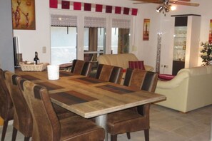 Un comedor con mesa y sillas de madera, un sofá y un ventilador de techo.