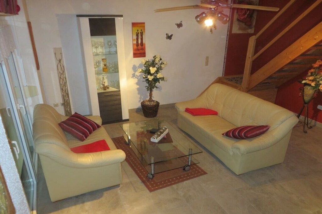 Ein Wohnzimmer mit zwei Sofas, einem Glastisch und einer Topfpflanze.