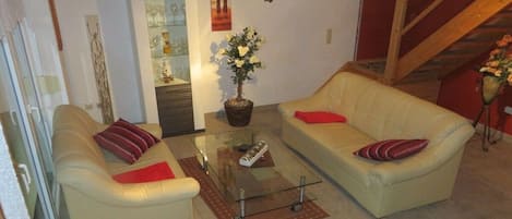 Un salon avec deux canapés, une table basse en verre et une plante en pot.
