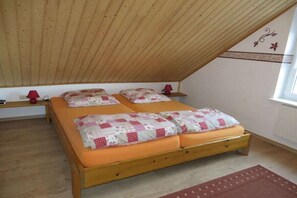 A bedroom with a sloped ceiling, a double bed with a quilt, bedside tables, and a window. - Annis Huus right on the water (Timmel)