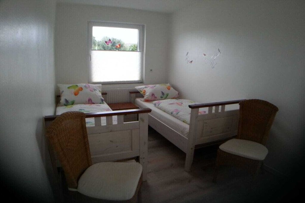 A room with two single beds, a window, and a chair.
