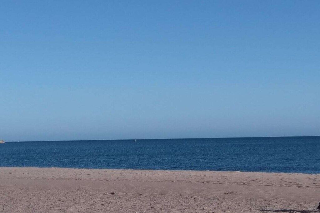 Une plage avec un ciel dégagé et une mer calme.