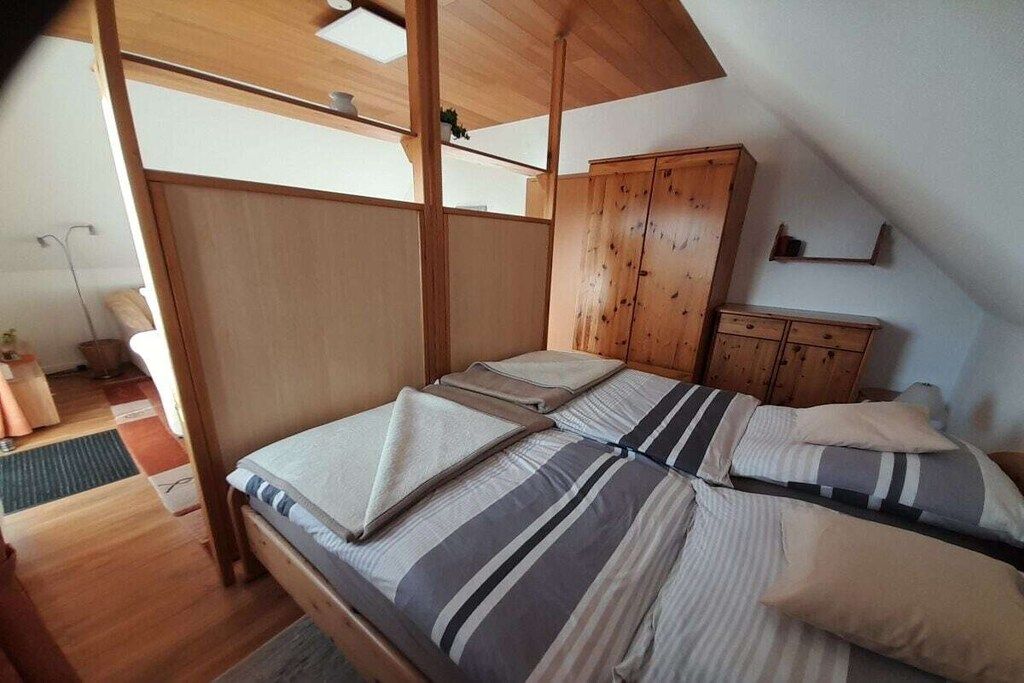 Una habitación con cama, armario de madera y techo inclinado.