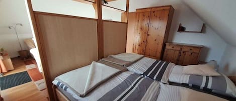 A room with a bed, wooden wardrobe, and a slanted ceiling.
