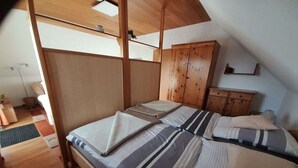 A bedroom with a wooden bed, a wardrobe, and a sloped ceiling. - Apartment in Kappeln with swimming pool (Kappeln)