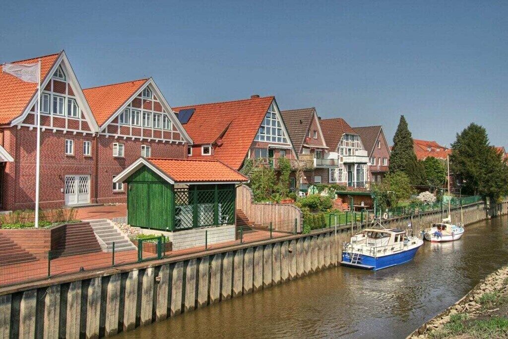 Een gebouw aan een kanaal, met een rode dakbedekking, een groene deur en een boot afgemeerd in de buurt.