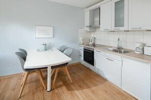 A modern kitchen with white cabinets, a white countertop, and a dining table with chairs. - Holiday apartment in Juist with swimming pool (Juist)
