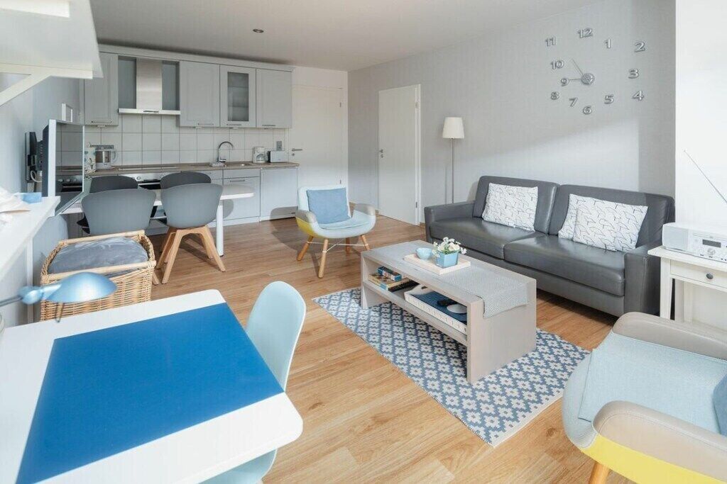 A modern living room with a sofa, chairs, a coffee table, and a dining area with a table and chairs.