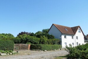 Une maison à deux étages avec un toit en pente, une allée pavée et une clôture en bois.