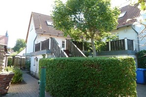 A residential property with a two-story house, a visible staircase, a hedge, and a brick wall. - Holiday apartment in Wiek with Wi-Fi (Wiek)