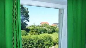 Ein Fenster mit Blick auf einen Garten und ein Gebäude mit rotem Dach.