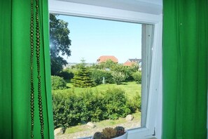 Ein Fenster mit Blick auf einen Garten und ein Gebäude mit rotem Dach.